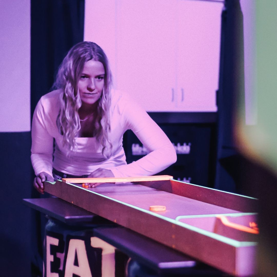 Konzentrierte Spielerin am Shuffleboard bei Beat Your Team Hannover