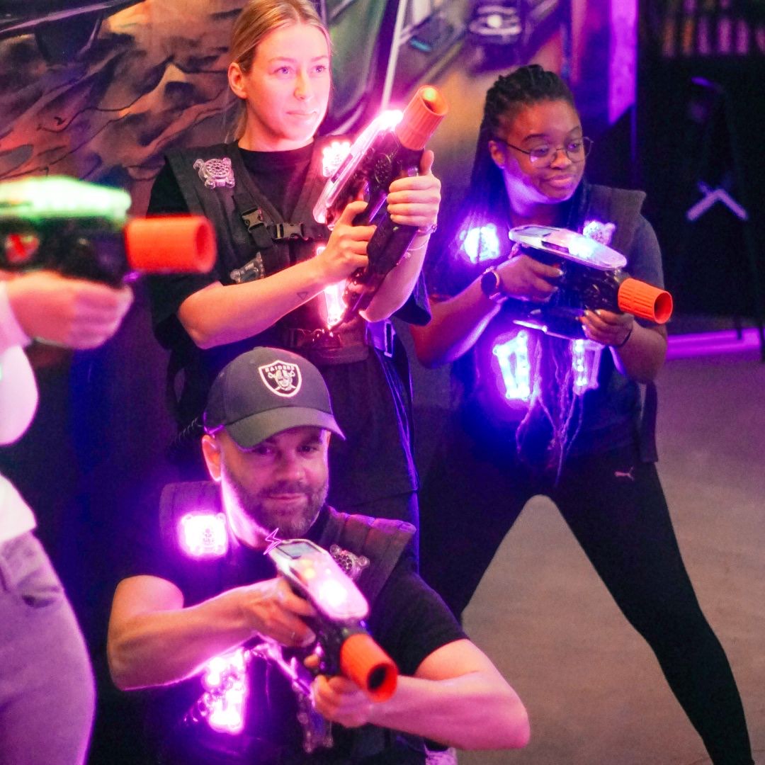 Drei Kollegen mit leuchtenden Lasertag-Westen beim Firmenevent